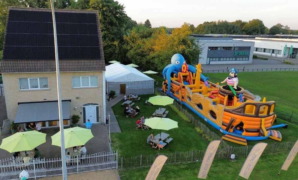 Luchtfoto met drone van Chocoberley in Herk-de-Stad: het gezellige zomerterras met tent en springkasteel, de winkel met ruime parking en de Sparxi-laadpalen"